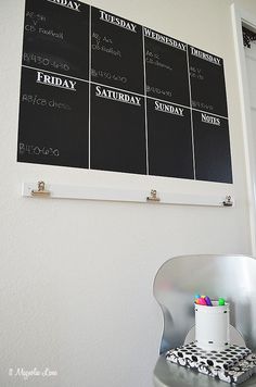 a black and white calendar hanging on the wall next to a chair with pens in it