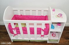 a white crib with pink bedding and accessories