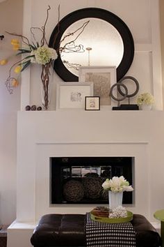 a living room filled with furniture and a fire place under a large round mirror on the wall