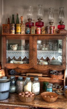 an old wooden cabinet filled with lots of jars and other items on top of a table