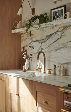 a kitchen with marble counter tops and gold faucets