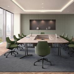 an empty conference room with green chairs and a large table in the middle, overlooking a cityscape