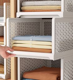 a person is reaching for some folded towels on a shelf in front of a closet