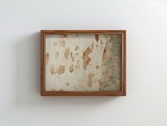 a painting hanging on the wall in an empty room with white walls and wooden frame