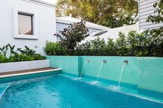 an outdoor swimming pool with blue tiles and water running from the side to the other side