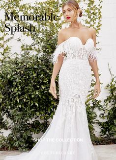 a woman in a white wedding dress standing next to some bushes and greenery with her hands on her hips