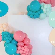 there are many balloons on the wall and one is pink, white, blue, and green