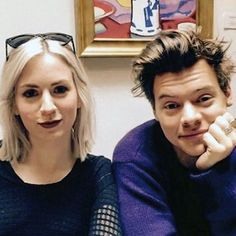 a man and woman sitting next to each other in front of a painting on the wall