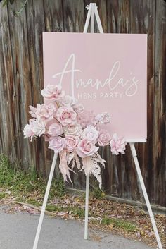 a pink sign that says amanda's hens party with flowers in front of it