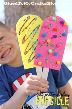 a young boy holding two popsicles covered in sprinkles and colored frosting