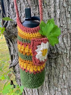 a crocheted bag hanging from a tree in front of a leafy branch