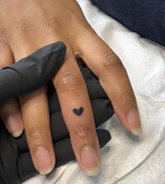 a person's hand with a small heart tattoo on it