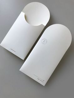 two white envelopes sitting next to each other on a gray surface with one open and the other closed