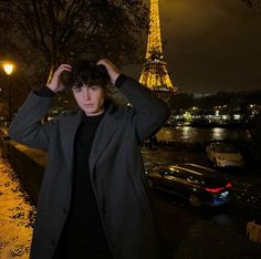 a man standing in front of the eiffel tower at night with his hands on his head