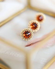 Add a touch of elegance to your everyday look with these stunning stud earrings featuring a dazzling combination of gold and topaz Swarovski crystals. The small beaded design with silver studs adds a touch of sophistication, while the dainty brown seed beads are accented with sparkling halo crystals for a touch of glamour. These earrings are the perfect accessory to elevate any outfit and make a statement. Handcrafted with love and attention to detail, these earrings are sure to become a favorit Elegant Amber Round Bead Earrings, Elegant Beaded Round Crystal Earrings, Elegant Round Beaded Crystal Earrings, Elegant Brown Crystal Earrings Gift, Elegant Brown Beaded Earrings, Elegant Brown Beaded Earrings As Gift, Small Beaded Earrings, Motifs Perler, Jewelry Care Instructions