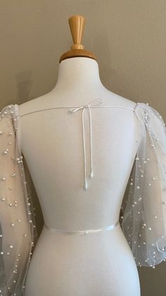 the back of a white dress on a mannequin headdress with pearls