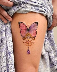 a woman's thigh with a pink butterfly tattoo on it and an ornate design