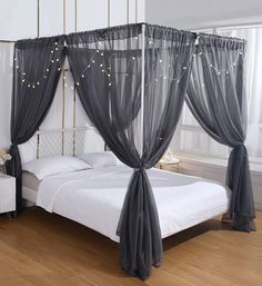 a bed with sheer curtains and lights on it