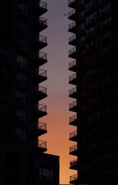 the sun is setting behind tall buildings with balconies and balconies on them