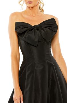 a woman wearing a black dress with a big bow