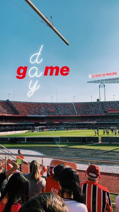 people are sitting in the stands at a baseball game and there is a neon sign that says it's game y