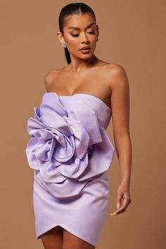 a woman in a short purple dress with a large flower on the front and side