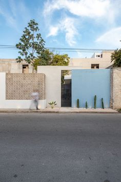 an empty street in front of a building with blue and white walls on the side