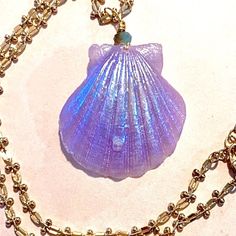 This is one of our famous and simply stunning seashell necklaces that have all of the beauty of a real looking shells combined with fantastic pops of color that become even more magical when they illuminate at night or in dark areas! This particular shell is the most beautiful shade of ultraviolet lilac quite similar to the shades that one would see in tropical flowers with an iridescent blue shimmer tonight it glows bright ocean blue suspended from a gold filled chain this item is sure to highl Handmade Mermaid-shaped Ocean-inspired Necklaces, Ocean-inspired Shell Necklaces For Gifts, Elegant Handmade Blue Shell Necklace, Spiritual Shell Necklace Gift, Ocean-inspired Mother Of Pearl Shell Necklace Gift, Ocean-inspired Mother Of Pearl Shell Necklace As Gift, Ocean-inspired Mother Of Pearl Shell Necklace For Gift, Unique Shell-shaped Shell Necklaces, Blue Shell-shaped Ocean-inspired Necklace