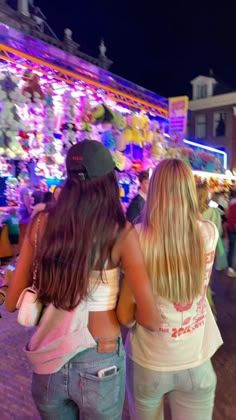 two girls are standing in front of a christmas light display at the fairground with their backs to each other