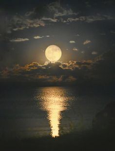 the full moon shines brightly in the night sky over the ocean with dark clouds