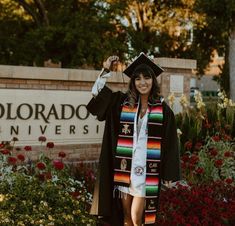 a woman in a graduation gown and cap is posing for a photo at the entrance to colorado university