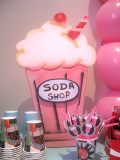 there is a soda shop display with pink and white balloons in the backround