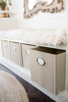 a white bench with drawers and a mirror on the wall