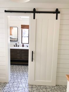 an open door leading to a bathroom with tile flooring and white walls in the background