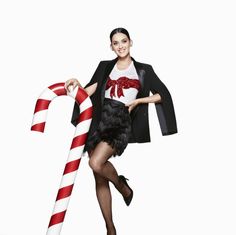 a woman is holding a candy cane and posing for the camera with her hands on her hips