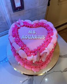 a heart shaped cake with the words ms aquarius on it sitting on a table