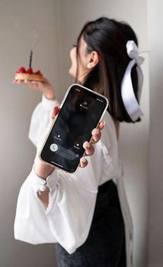 a woman holding an iphone in her right hand and looking at the phone screen while she holds