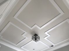 the ceiling in this room is painted white and has geometric designs on it, with a black square light fixture hanging from the ceiling