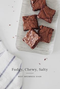 four pieces of brownie sitting on top of a white plate next to a towel