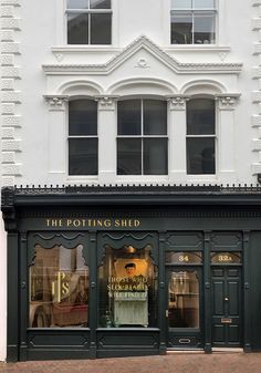 the potting shed is located on the corner of this street in front of a white building