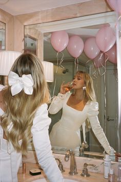 a woman in a white dress is brushing her teeth while looking at herself in the mirror