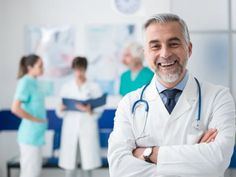 a smiling doctor with his arms crossed in front of other doctors