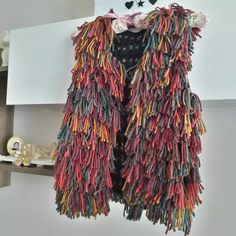 a multicolored jacket hanging on a wall next to a shelf with other items