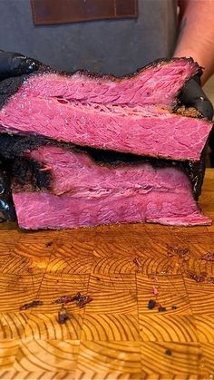 two pieces of meat sitting on top of a wooden cutting board