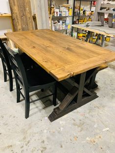 a wooden table surrounded by black chairs in a room filled with shelves and other items