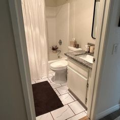 a bathroom with a toilet, sink and shower curtain in it's door way