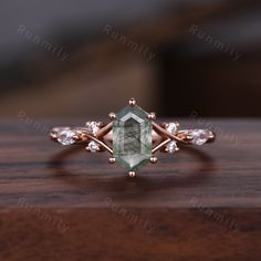 a ring with an oval cut green stone surrounded by small white diamonds on a wooden surface