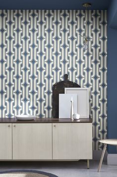 a blue and white patterned wallpaper in a living room with a wooden cabinet next to it