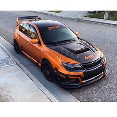 an orange and black car parked on the side of a road next to a curb