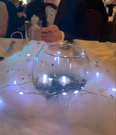 a man in a tuxedo sitting at a table with a fish bowl on it